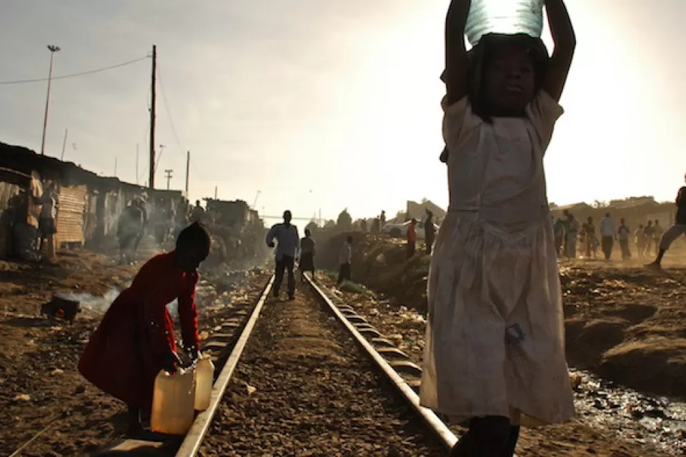 Two young girls carry water on the train tracks that run through the Kibera Slum